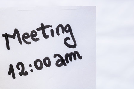 Meeting handwriting text close up isolated on white paper with copy space. Writing text on memo post...