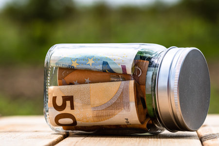 Composition with saving money banknotes in a glass jar. Concept of investing and keeping money,...