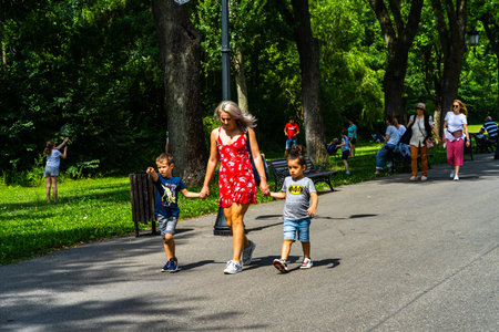 Mother with her kids walking, relaxing and have fun on the alleys of park and gardens of the domain...
