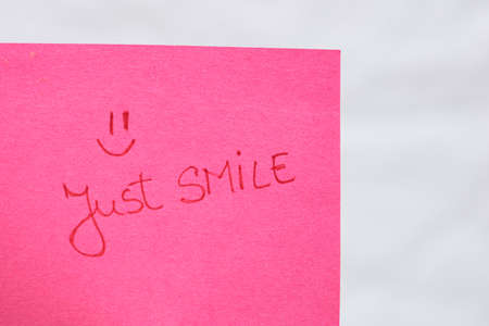 Just smile handwriting text close up isolated on pink paper with copy space. Writing text on memo post reminderの写真素材