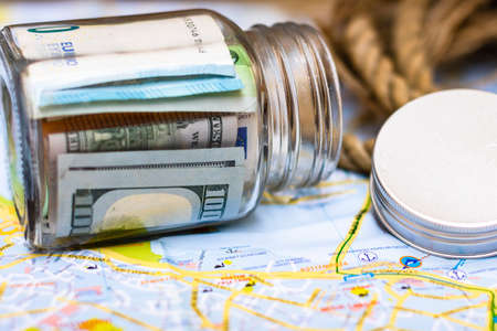 Composition with saving money banknotes in a glass jar. Concept of investing and keeping money for dreams and travel, close up isolated.の写真素材