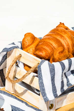 Fresh croissant, puff pastry and buttered french croissant on wooden crate. Food and breakfast concept. Detail of desserts and fresh pastriesの写真素材