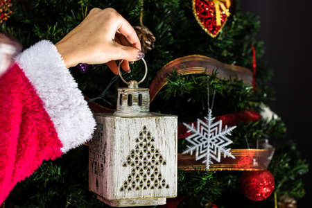 Hands holding Christmas ornament in front of Christmas tree. Decorating fir branches with Christmas decorations.の写真素材