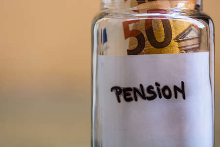 Composition with saving money banknotes in a glass jar with text pension .Concept of investing and keeping money, close up isolated.の写真素材