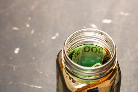 Composition with saving money banknotes in a glass jar. Concept of investing and keeping money, close up isolated.の写真素材