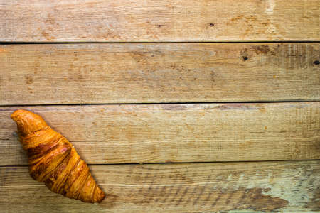 Detail of fresh croissant on wooden table. Food and breakfast concept. Top view and copy spaceの写真素材