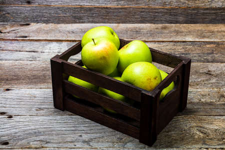 Wooden crate with ripe green apples on wooden table.の写真素材