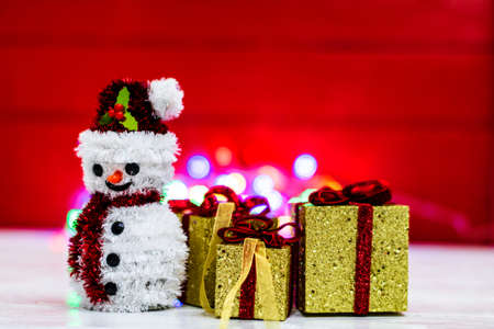 Snowman Christmas figurine near glittery gifts isolated on blurred background of lights. Christmas decorations isolatedの写真素材