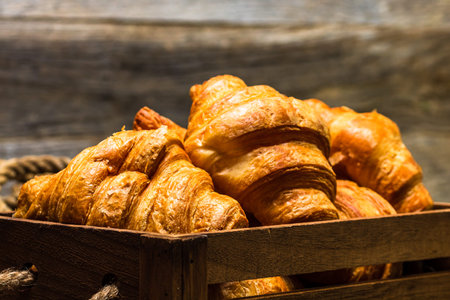 Wooden crate with delicious, fresh croissants isolated. French breakfast concept.