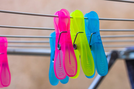 Colorful plastic clothes pegs on empty metal clothes dryer.