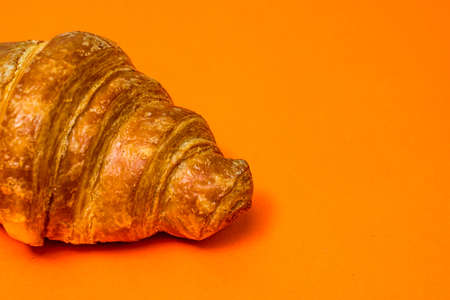 Fresh croissant isolated on orange board. French breakfast concept.の写真素材