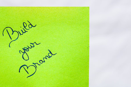 Build your brand handwriting text close up isolated on green paper with copy space. Writing text on...