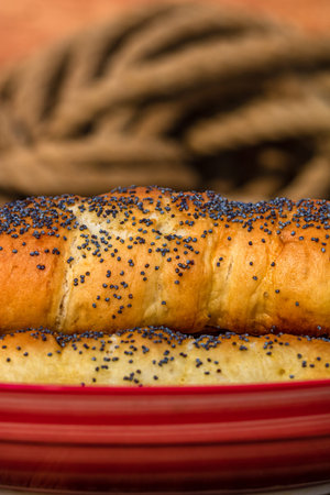 Sausages baked in dough sprinkled with salt and poppy seeds in a rustic composition. Sausages rolls,...