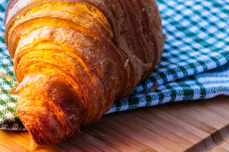 Detail of fresh croissant on wooden table. Food and breakfast concept. Close up photo of French...