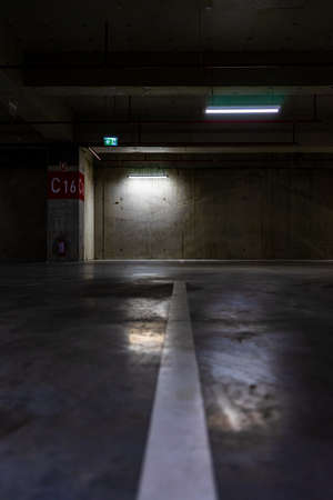 Empty parking lot with overhead dim light, underground parking garage.の写真素材