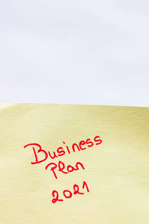 Business plan 2021 handwriting text close up isolated on yellow paper with copy space.の写真素材