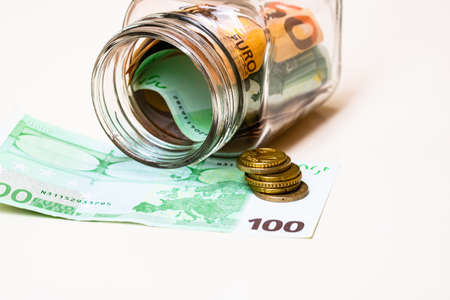 Composition with saving money banknotes in a glass jar. Concept of investing and keeping money, close up isolated.の写真素材