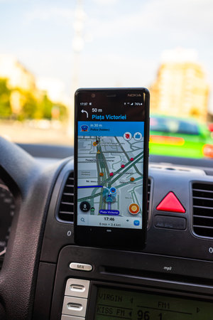 In car dashboard view with smartphone showing Police on Waze maps. Driver using Waze maps in...