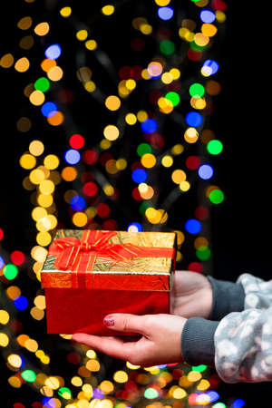 Woman's hands hold christmas decoration. Christmas and New Year holidays background, winter season with Christmas ornaments and blurred lightsの写真素材
