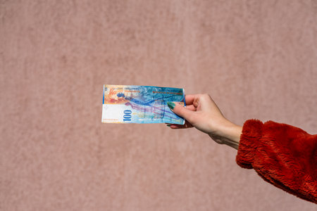 Hand holding showing euro money and giving or receiving money like tips, salary. 100 swiss franc banknotes CHF currency isolated. Concept of rich business people, saving or spending money.の写真素材