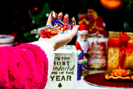 Hands holding candies in front of Christmas tree. Unpacking Christmas gifts isolated.の写真素材