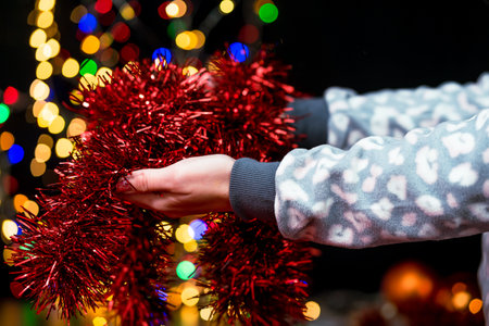 Woman's hands hold christmas decoration. Christmas and New Year holidays background, winter season with Christmas ornaments and blurred lightsの写真素材