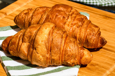 Detail of fresh croissant on wooden table. Food and breakfast concept. Close up photo of French...