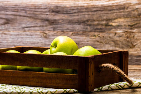 Wooden crate with ripe green apples on wooden table.の写真素材