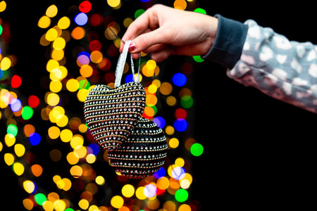 Woman's hands hold christmas decoration. Christmas and New Year holidays background, winter season with Christmas ornaments and blurred lightsの写真素材
