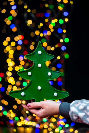 Woman's hands hold christmas decoration. Christmas and New Year holidays background, winter season with Christmas ornaments and blurred lightsの写真素材