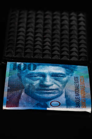 100 swiss franc banknote in a black wallet isolated.の写真素材