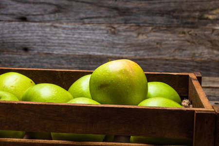 Wooden crate with ripe green apples on wooden table.の写真素材