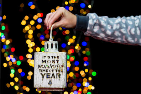 Woman's hands hold christmas decoration. Christmas and New Year holidays background, winter season with Christmas ornaments and blurred lightsの写真素材