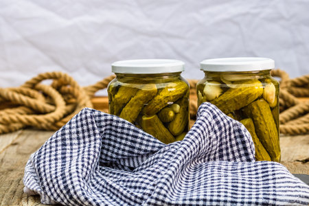 Glass jars with pickled red bell peppers and pickled cucumbers (pickles) isolated. Jars with variety...