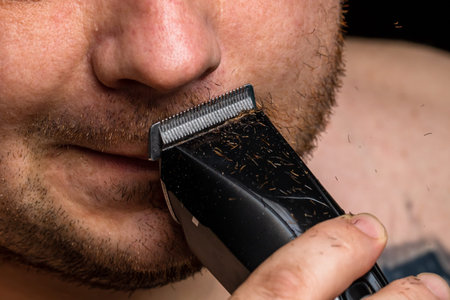 Man shaving or trimming his beard using a hair clipper