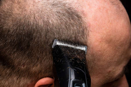 Man shaving or trimming his hair using a hair clipperの写真素材