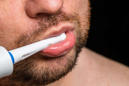 Close up of man brushing his teeth with electric toothbrushの写真素材