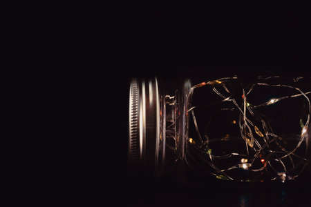Colorful fairy lights in glass jar isolated on black background.の写真素材