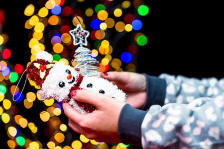 Woman's hands hold christmas decoration. Christmas and New Year holidays background, winter season with Christmas ornaments and blurred lightsの写真素材
