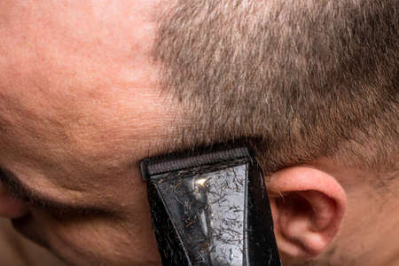 Man shaving or trimming his hair using a hair clipperの写真素材