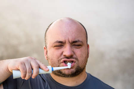 Male brushing his teeth with electric toothbrushの写真素材