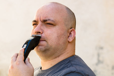 Male shaving or trimming his beard using a hair clipper or electric razor