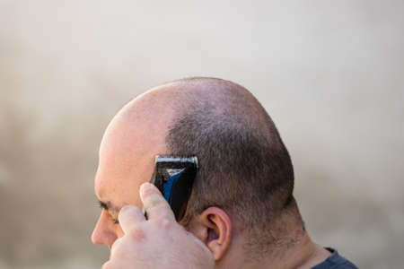 Male shaving or trimming his hair using a hair clipper or electric razorの写真素材