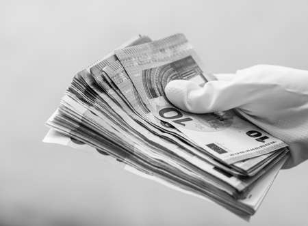 World money concept, hand with gloves receiving, giving or holding EURO banknote, isolated on blurred background. Corona virus COVID-19 outbreak. Concept of prevention virus spreadの写真素材
