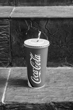 Paper cup with Coca Cola left on stairs in public place in Bucharest, Romania, 2021