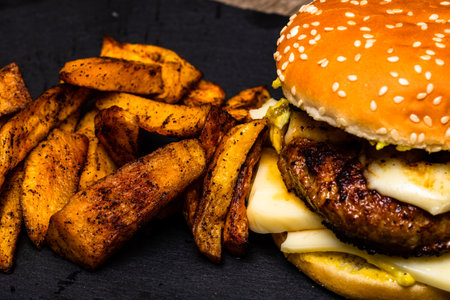 Homemade fresh tasty cheese burger and fried potatoes on a wooden tableの写真素材