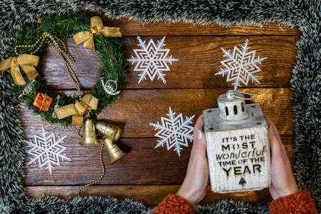 Christmas composition on wooden board with Christmas garland and decorations. Hands holding Christmas decorations.の写真素材