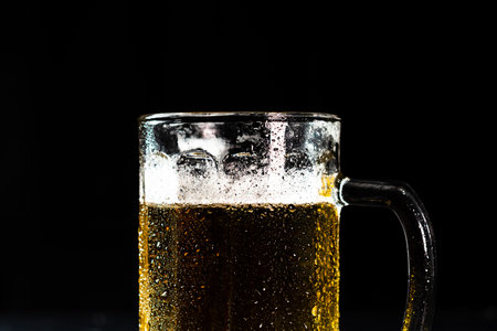 Glass of beer with beer foam on dark background