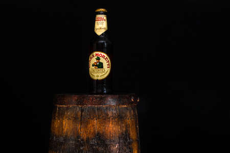 Bottle of Birra Moretti beer on wooden barrel with dark background. Illustrative editorial photo Bucharest, Romania, 2021のeditorial素材
