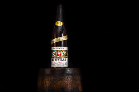 Vintage Murfatlar wine bottle on wooden barrel with dark background. Illustrative editorial photo Bucharest, Romania, 2021のeditorial素材